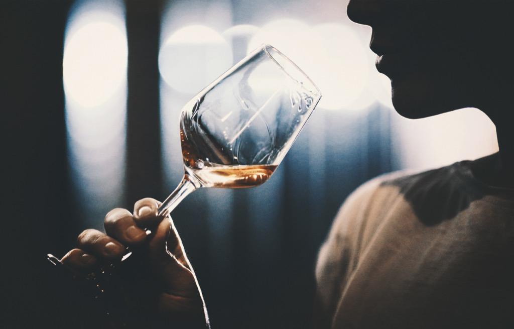 Iemand proeft een glas witte wijn