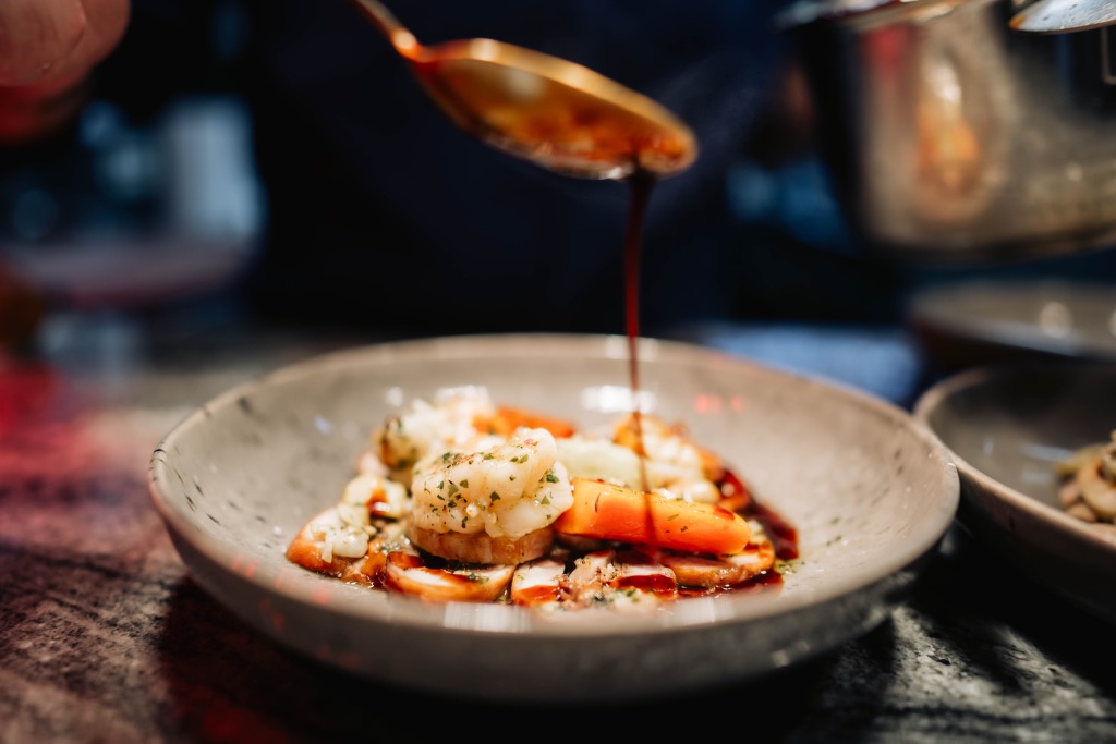 Saus wordt over een opgemaakt gerecht geschonken